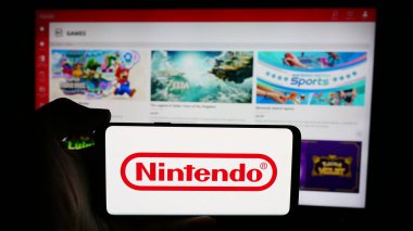 Stuttgart, Almanya - 07-19-2024: Japon video oyunu şirketi Nintendo Co. Ltd. nin logosuyla cep telefonu tutan kişi iş sayfasının önünde. Telefon ekranına odaklan.