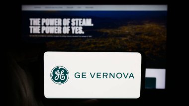 Stuttgart, Almanya - 07-19-2024: ABD 'li enerji donanım şirketi GE Vernova Inc.' in logosuyla cep telefonu sahibi kişi iş sayfasının önünde. Telefon ekranına odaklan.