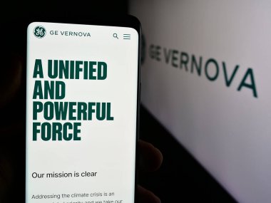 Stuttgart, Almanya - 07-19-2024: ABD 'li enerji donanım şirketi GE Vernova Inc.' in web sayfası ile logo önünde cep telefonu bulunduran kişi. Telefon ekranının merkezine odaklan.
