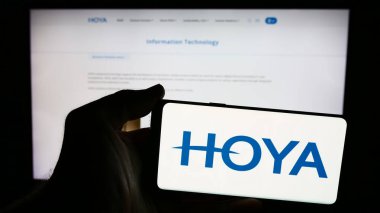 Stuttgart, Almanya - 07-19-2024: Japon hassas enstrüman şirketi Hoya Corporation 'ın logosuna sahip akıllı telefon sahibi kişi web sitesinin önünde. Telefon ekranına odaklan.