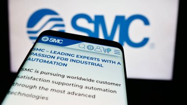 Stuttgart, Germany - 07-25-2024: Mobile phone with website of Japanese machinery company SMC Corporation in front of business logo. Focus on top-left of phone display. clipart