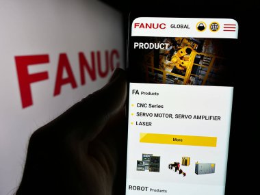 Stuttgart, Almanya - 07-25-2024: Japon robotik şirketi FANUC Corporation 'ın internet sayfası ile logo önünde cep telefonu tutan kişi. Telefon ekranının merkezine odaklan.