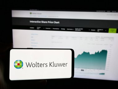 Stuttgart, Almanya - 07-25-2024: Hollandalı bilgi hizmetleri şirketi Wolters Kluwer NV 'nin logosunun bulunduğu cep telefonu web sayfasının önünde duruyor. Telefon ekranına odaklan.