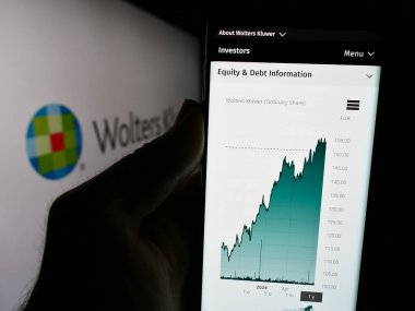 Stuttgart, Almanya - 07-25-2024: Hollandalı bilgi hizmetleri şirketi Wolters Kluwer N.V. 'nin logolu web sitesi ile cep telefonu tutan kişi. Telefon ekranının merkezine odaklan.