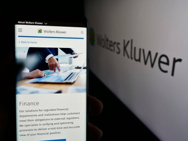 Stuttgart, Almanya - 07-25-2024: Hollandalı bilgi hizmetleri şirketi Wolters Kluwer N.V. 'nin logolu web sayfası ile cep telefonu tutan kişi. Telefon ekranının merkezine odaklan.