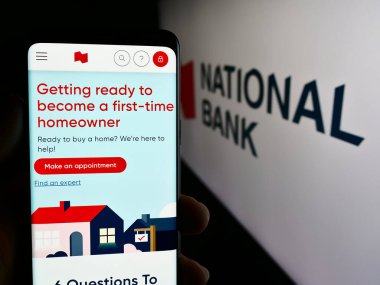Stuttgart, Almanya - 07-19-2024: Kanada Ulusal Bankası (NBC) finans hizmetleri şirketinin logolu web sayfası ile cep telefonu tutan kişi. Telefon ekranının merkezine odaklan.