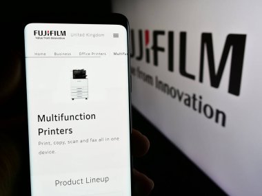 Stuttgart, Almanya - 07-19-2024: Japon şirketi Fujifilm Holding Corporation 'ın logo önündeki web sayfası ile cep telefonu tutan kişi. Telefon ekranının merkezine odaklan.