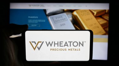 Stuttgart, Almanya - 07-19-2024: Kanadalı metal şirketi Wheaton Precious Metals Corp 'un logosunun bulunduğu cep telefonu sahibi kişi iş sayfasının önünde. Telefon ekranına odaklan.