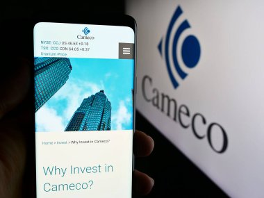 Stuttgart, Almanya - 07-21-2024: Kanadalı uranyum madencilik şirketi Cameco Corporation 'ın logo önündeki web sayfası ile cep telefonu tutan kişi. Telefon ekranının merkezine odaklan.