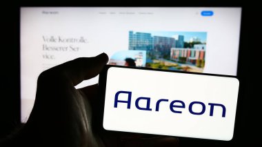 Stuttgart, Almanya - 07-21-2024: Alman emlak yazılım şirketi Aareon AG 'nin logosunu taşıyan cep telefonu sahibi iş sayfası önünde. Telefon ekranına odaklan.