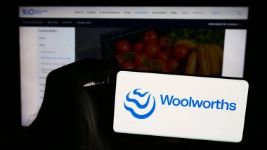 Stuttgart, Almanya - 07-21-2024: Avustralyalı perakende şirketi Woolworths Group Limited 'in logosuna sahip akıllı telefon sahibi kişi web sitesi önünde. Telefon ekranına odaklan.