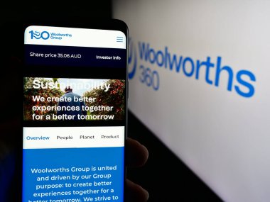 Stuttgart, Almanya - 07-21-2024: Avustralyalı perakende şirketi Woolworths Group Limited 'in web sayfası olan akıllı telefon sahibi kişi logo önünde bulunuyor. Telefon ekranının merkezine odaklan.