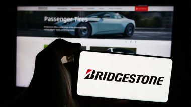 Stuttgart, Almanya - 07-21-2024: Japon lastik şirketi Bridgestone Corporation 'ın logosunun bulunduğu akıllı telefonu web sitesinin önünde tutan kişi. Telefon ekranına odaklan.