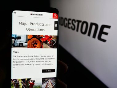 Stuttgart, Almanya - 07-21-2024: Japon lastik şirketi Bridgestone Corporation 'ın internet sayfası ile logo önünde cep telefonu tutan kişi. Telefon ekranının merkezine odaklan.