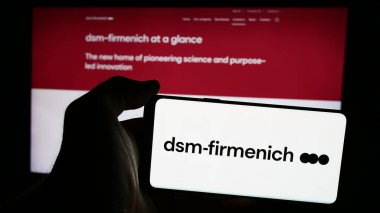 Stuttgart, Almanya - 07-21-2024: İsviçreli kimya şirketi DSM-Firmenich AG 'nin logosuna sahip akıllı telefon sahibi kişi web sitesi önünde. Telefon ekranına odaklan.