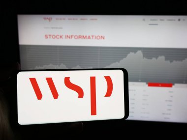 Stuttgart, Almanya - 07-21-2024: Kanadalı danışmanlık şirketi WSP Global Inc. 'in logosuna sahip cep telefonu sahibi kişi iş sayfasının önünde. Telefon ekranına odaklan.