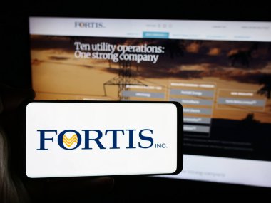 Stuttgart, Almanya - 07-23-2024: Kanadalı elektrik şirketi Fortis Inc. 'in logosuna sahip akıllı telefon sahibi kişi web sitesinin önünde. Telefon ekranına odaklan.