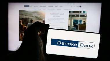 Stuttgart, Almanya - 07-23-2024: Danimarkalı finans hizmetleri şirketi Danske Bank AS 'nin logosunun bulunduğu akıllı telefon sahibi kişi web sitesinin önünde. Telefon ekranına odaklan.