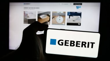 Stuttgart, Almanya - 07-23-2024: İsviçreli hijyen ürünleri şirketi Geberit AG 'nin logosuna sahip akıllı telefon sahibi kişi web sitesi önünde. Telefon ekranına odaklan.