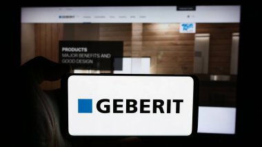 Stuttgart, Almanya - 07-23-2024: İsviçreli hijyen ürünleri şirketi Geberit AG 'nin logosunun bulunduğu cep telefonu sahibi kişi iş sayfasının önünde. Telefon ekranına odaklan.