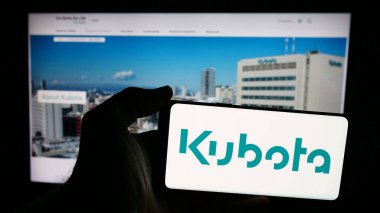 Stuttgart, Almanya - 07-23-2024: Japon ağır ekipman şirketi Kubota Corporation 'ın logosuna sahip akıllı telefon sahibi kişi web sitesinin önünde. Telefon ekranına odaklan.