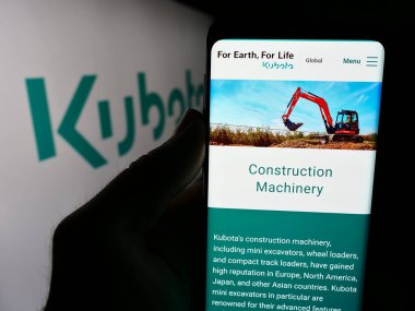 Stuttgart, Almanya - 07-23-2024: Japon ağır ekipman şirketi Kubota Corporation logosu web sitesi ile cep telefonu tutan kişi. Telefon ekranının merkezine odaklan.