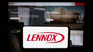 Stuttgart, Almanya - 07-23-2024: ABD 'li HVAC ekipman şirketi Lennox International Inc.' in logosuyla cep telefonu sahibi kişi iş sayfası önünde. Telefon ekranına odaklan.