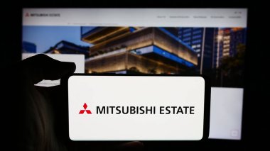 Stuttgart, Almanya - 07-23-2024: İnternet sayfası önünde Japon emlak şirketi Mitsubishi Estate Co. Ltd. (MEC) logosuna sahip kişi. Telefon ekranına odaklan.