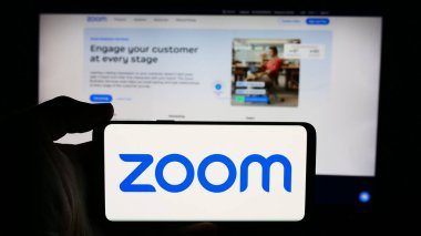 Stuttgart, Almanya - 07-24-2024: İnternet sayfası önünde ABD 'li iletişim şirketi Zoom Video Communications Inc.' in logosuyla cep telefonu tutan kişi. Telefon ekranına odaklan.