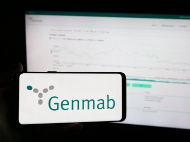 Stuttgart, Almanya - 07-24-2024: Danimarkalı biyoteknoloji şirketi Genmab AS 'in logosunu taşıyan cep telefonu sahibi şirket web sitesi önünde. Telefon ekranına odaklan.
