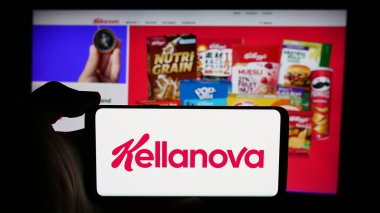 Stuttgart, Almanya - 07-24-2024: ABD gıda işleme şirketi Kellanova Company 'nin logosunun bulunduğu cep telefonu sahibi kişi iş sayfası önünde. Telefon ekranına odaklan.