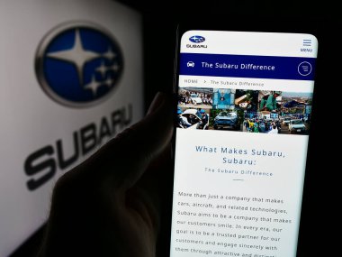 Stuttgart, Almanya - 07-25-2024: Japon şirketi Subaru Corporation 'ın internet sayfası ile iş logosu önünde akıllı telefon tutan kişi. Telefon ekranının merkezine odaklan.