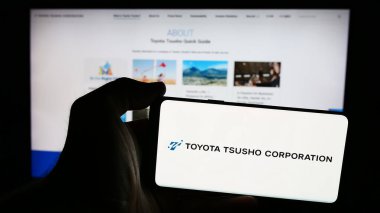 Stuttgart, Almanya - 07-25-2024: Japon ticaret şirketi Toyota Tsusho Corporation 'ın logosuna sahip akıllı telefon sahibi kişi web sitesinin önünde. Telefon ekranına odaklan.