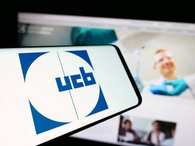Stuttgart, Almanya - 07-25-2024: Belçikalı biyofarmasötik şirketi UCB SA 'nın logosunun yer aldığı cep telefonu. Telefon ekranının merkez soluna odaklan.