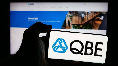 Stuttgart, Almanya - 07-25-2024: Avustralyalı QBE Sigorta Grubu 'nun logosuna sahip akıllı telefon sahibi kişi web sitesi önünde Limited. Telefon ekranına odaklan.