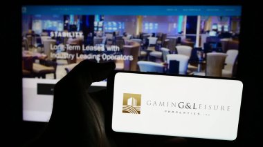 Stuttgart, Almanya - 07-29-2024: İnternet sitesi önünde ABD 'li emlak şirketi Gaming and Leisure Properties Inc.' in logosuna sahip kişi. Telefon ekranına odaklan.
