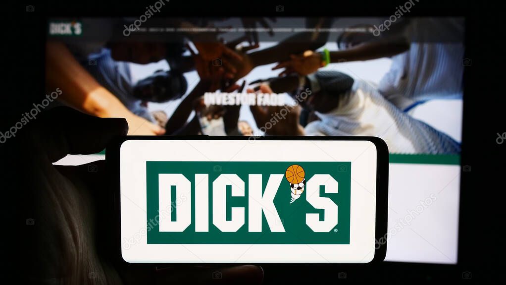 Stuttgart, Germany - 07-29-2024: Person holding cellphone with logo of US retail company Dick's Sporting Goods Inc. in front of business webpage. Focus on phone display.