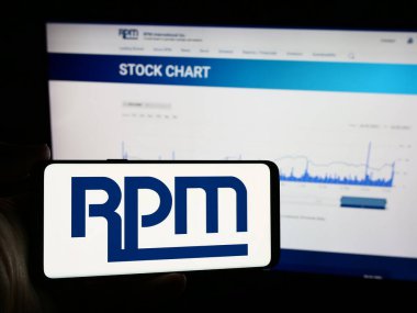 Stuttgart, Almanya - 07-29-2024: Amerikan kaplama şirketi RPM International Inc. 'in logosunun bulunduğu cep telefonu sahibi kişi iş sayfasının önünde. Telefon ekranına odaklan.