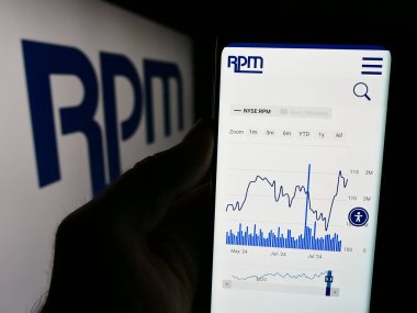 Stuttgart, Almanya - 07-29-2024: ABD 'li kaplama şirketi RPM International Inc.' in web sitesi ile iş logosu önünde cep telefonu tutan kişi. Telefon ekranının merkezine odaklan.
