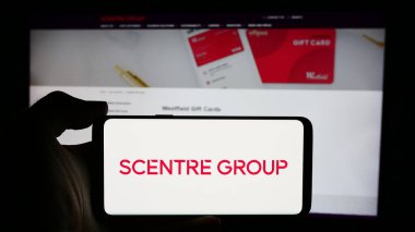 Stuttgart, Almanya - 07-29-2024: Avustralyalı alışveriş merkezi şirketi Scenter Group Limited 'in logosuna sahip cep telefonu sahibi kişi web sayfasının önünde. Telefon ekranına odaklan.