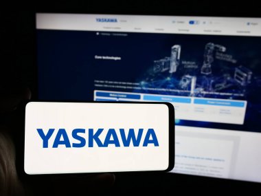 Stuttgart, Almanya - 07-30-2024: Japon şirketi Yaskawa Electric Corporation 'ın logosuna sahip akıllı telefon sahibi kişi web sitesi önünde. Telefon ekranına odaklan.