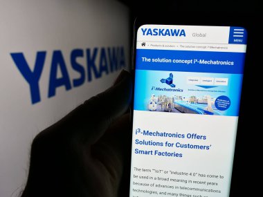 Stuttgart, Almanya - 07-30-2024: Japon şirketi Yaskawa Electric Corporation 'ın web sitesi ile logo önünde akıllı telefon taşıyan kişi. Telefon ekranının merkezine odaklan.