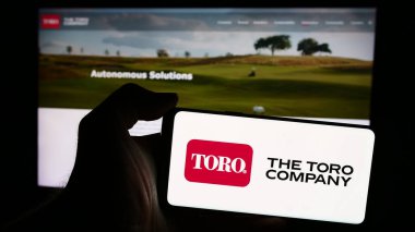 Stuttgart, Almanya - 07-30-2024: Üzerinde Amerikan çim biçme makinesi şirketi logosu olan cep telefonu tutan kişi The Toro Company iş sayfasının önünde. Telefon ekranına odaklan.