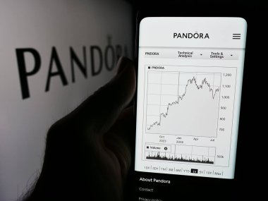 Stuttgart, Almanya - 07-30-2024: Danimarkalı mücevher şirketi Pandora AS 'nin web sitesi ile iş logosu önünde cep telefonu tutan kişi. Telefon ekranının merkezine odaklan.