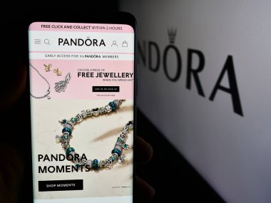 Stuttgart, Almanya - 07-30-2024: Danimarkalı mücevher şirketi Pandora AS 'nin web sayfası ile akıllı telefon taşıyan kişi iş logosu önünde. Telefon ekranının merkezine odaklan.