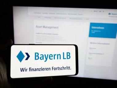 Stuttgart, Almanya - 07-31-2024: İnternet sayfası önünde Alman finans şirketi Bayerische Landesbank 'ın (BayernLB) logosuna sahip cep telefonu sahibi kişi. Telefon ekranına odaklan.
