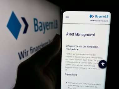 Stuttgart, Almanya - 07-31-2024: Alman finans şirketi Bayerische Landesbank 'ın (BayernLB) logolu web sayfası ile cep telefonu tutan kişi. Telefon ekranının merkezine odaklan.