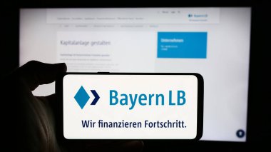 Stuttgart, Almanya - 07-31-2024: İnternet sayfası önünde Alman finans şirketi Bayerische Landesbank 'ın (BayernLB) logosuyla cep telefonu tutan kişi. Telefon ekranına odaklan.