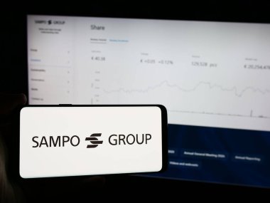 Stuttgart, Germany - 08-09-2024: Person holding mobile phone with logo of Finnish insurance company Sampo Oyj in front of business web page. Focus on phone display. clipart