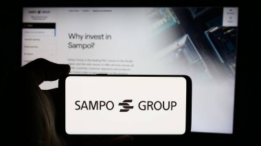 Stuttgart, Almanya - 08-09-2024: İş sayfası önünde Fin sigorta şirketi Sampo Oyj 'un logosuyla cep telefonu tutan kişi. Telefon ekranına odaklan.